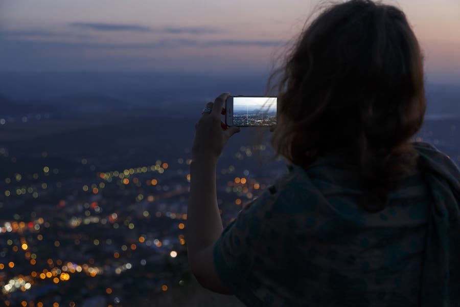 woman taking a picture of the city lights outdoors