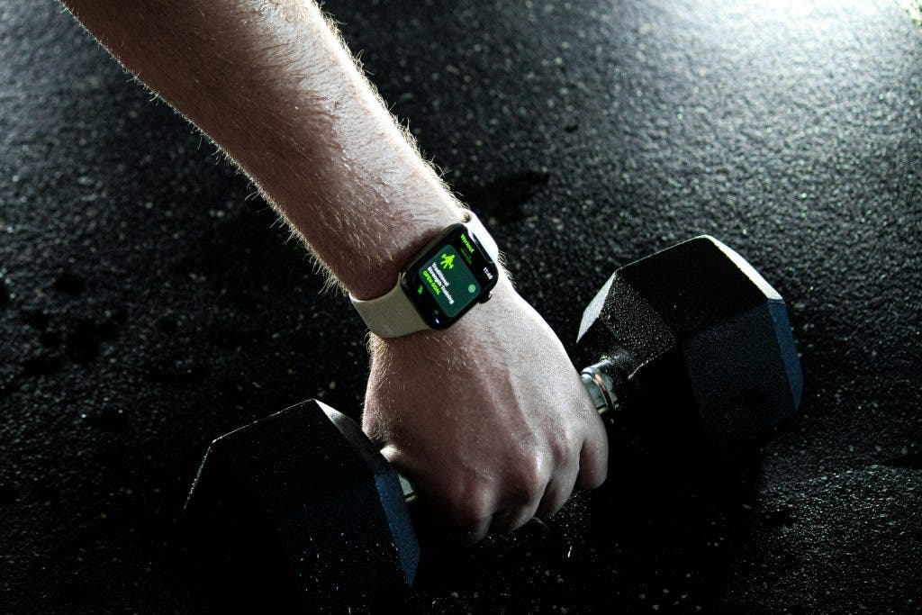 man grabs dumbbell during strength training with his fitness tracker